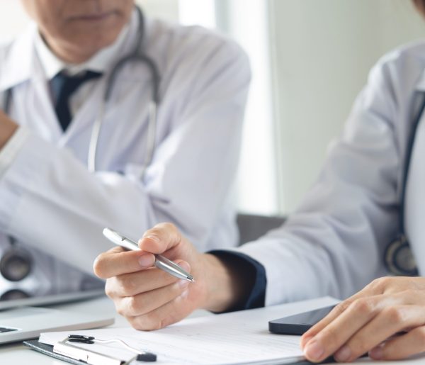 Two,Asian,Doctors,Discuss,Diagnosis,,Analyzing,Data,On,Laptop,In